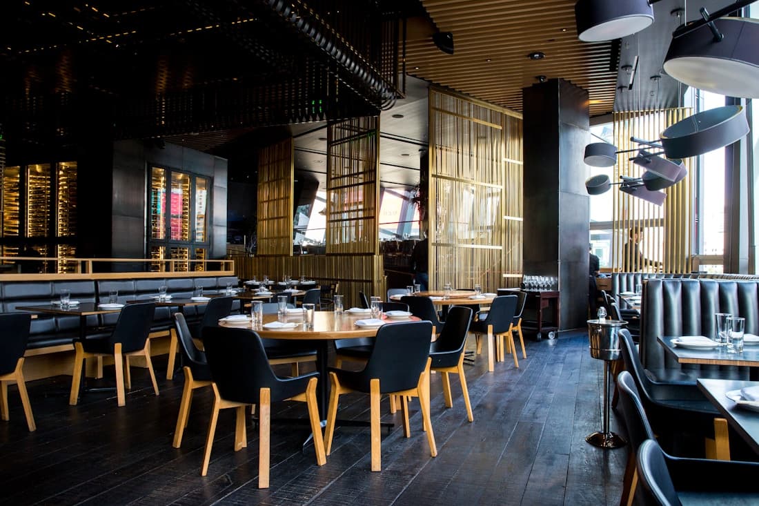 Yeşil bitkiler, ahşap masalar ve sıcak ışıklarla hazırlanmış restoran